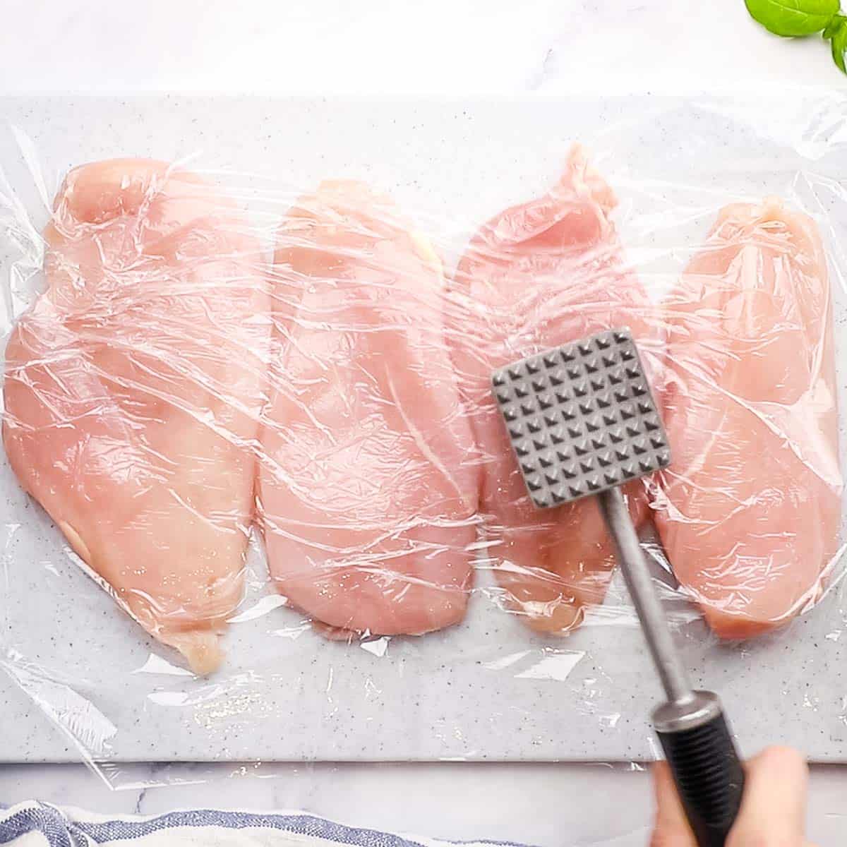 pounding the chicken breasts with a meat mallet