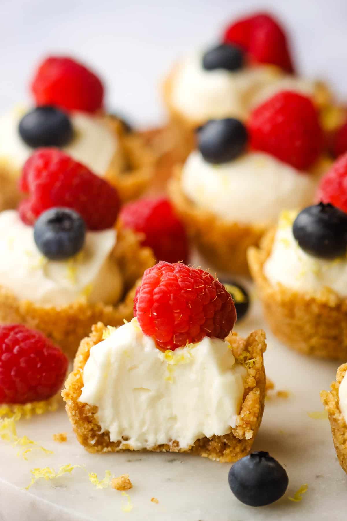 A mini cheesecake tart with a bite out of it to show the inside.