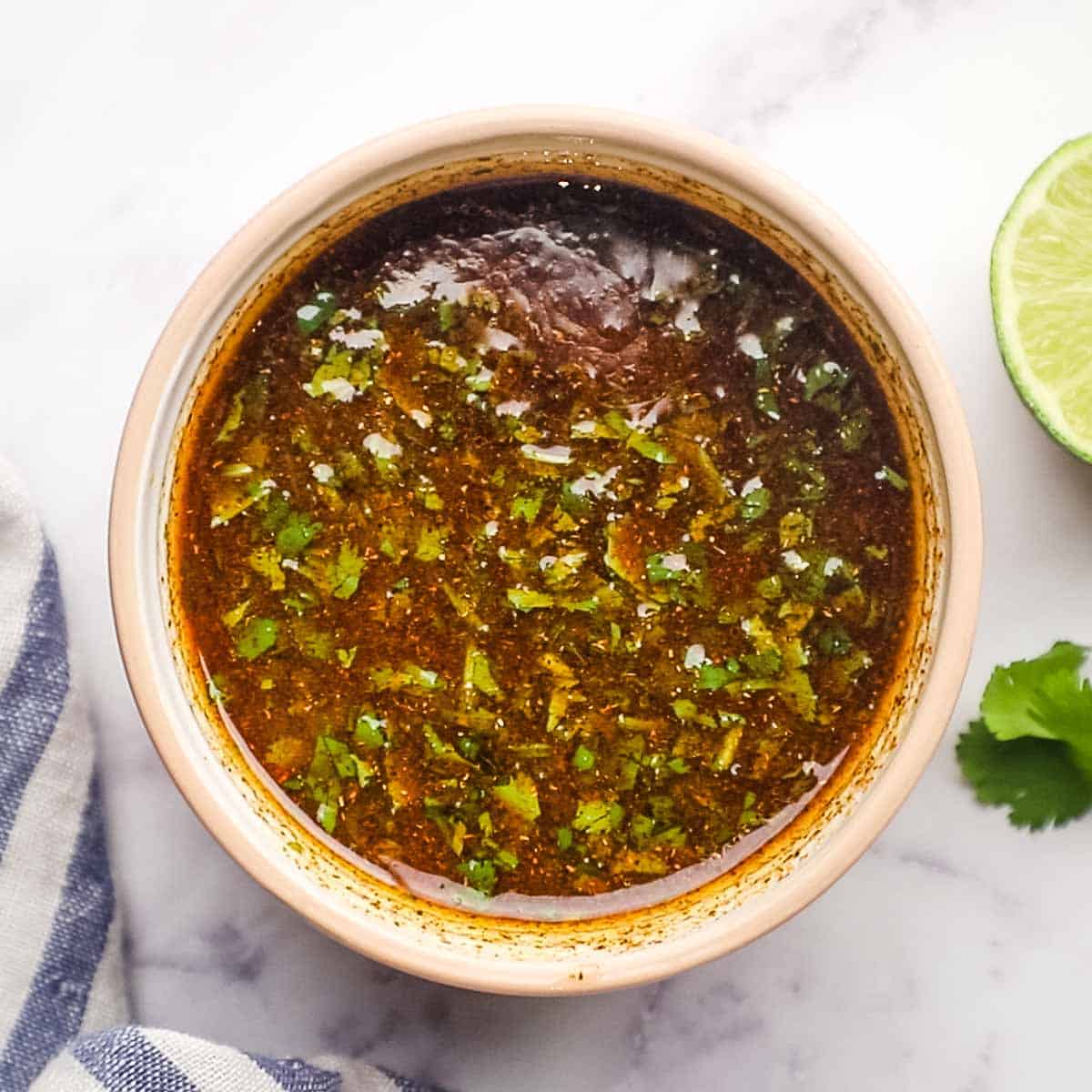 A bowl of dressing with chili powder and cilantro.