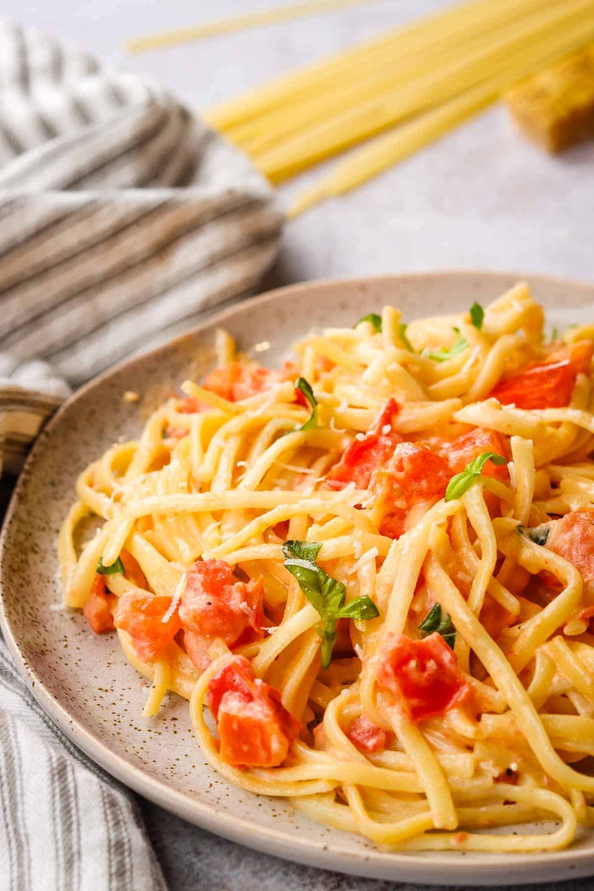 Side view of a plate of linguine with creamy tomato sauce.