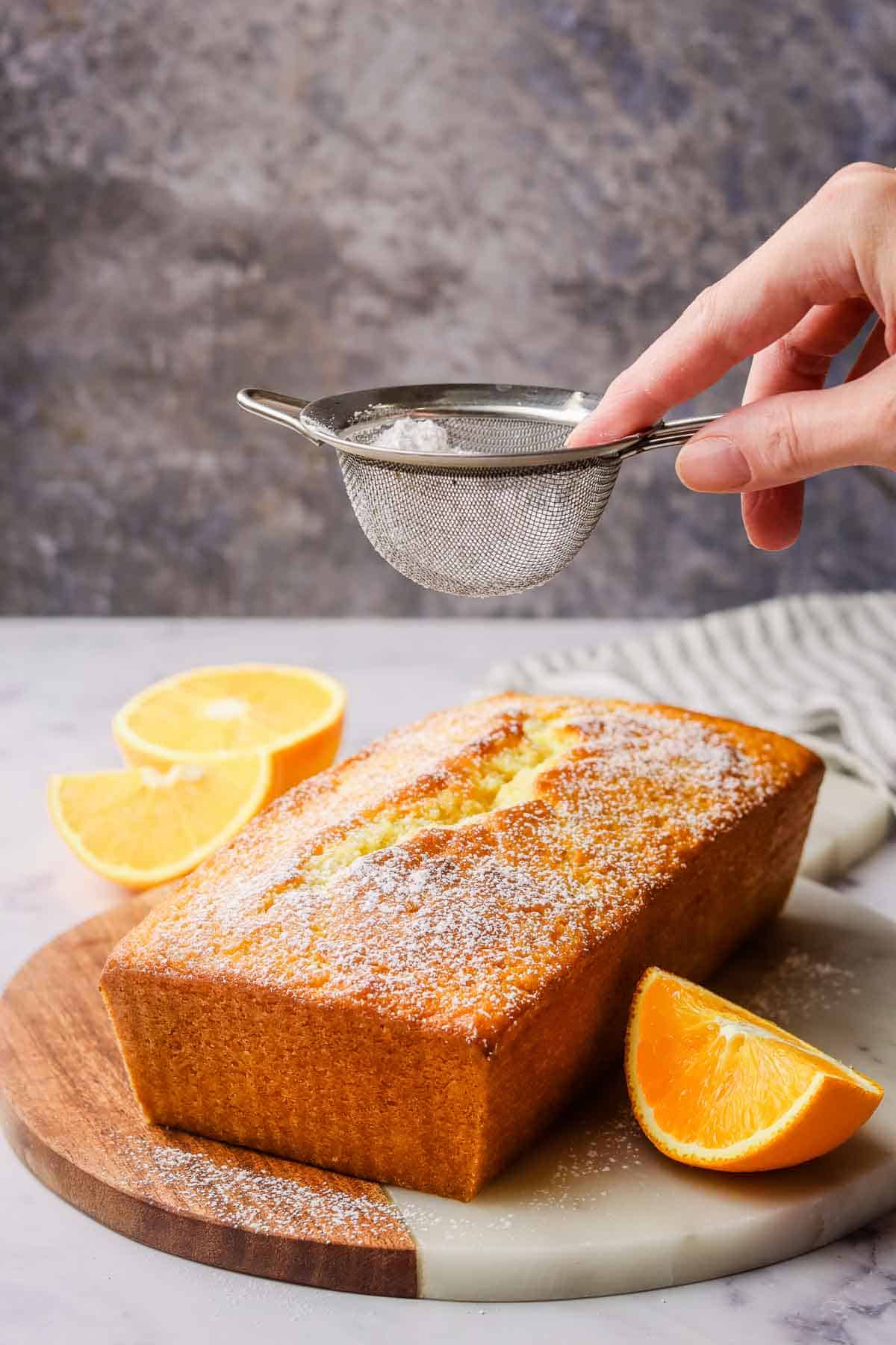 dusting the orange loaf cake with icing sugar