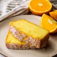 Two thick slices of orange loaf cake on a plate.