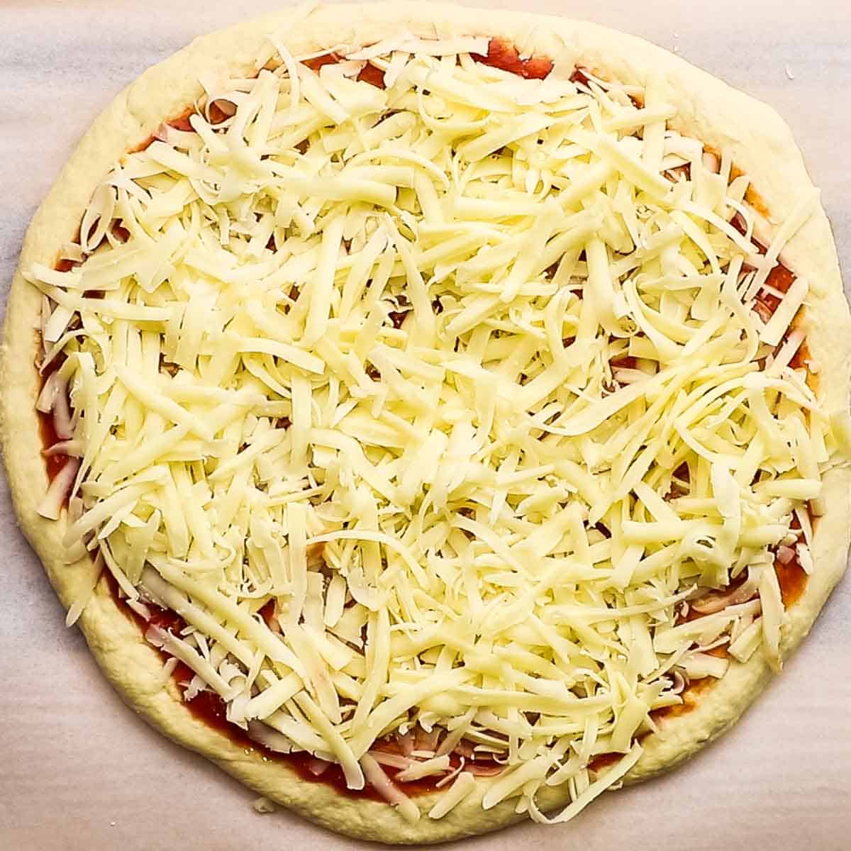grated cheese spread on top of the pizza