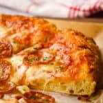 Side view of a slice of thick crust pizza with pepperoni.