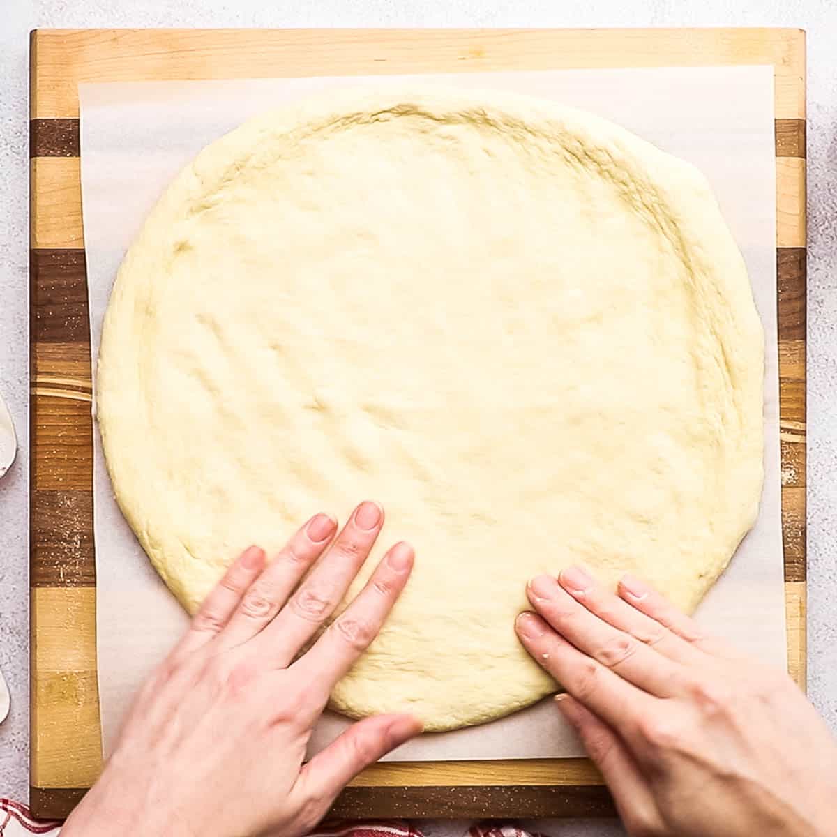 Pizza dough being stretched into a circle.
