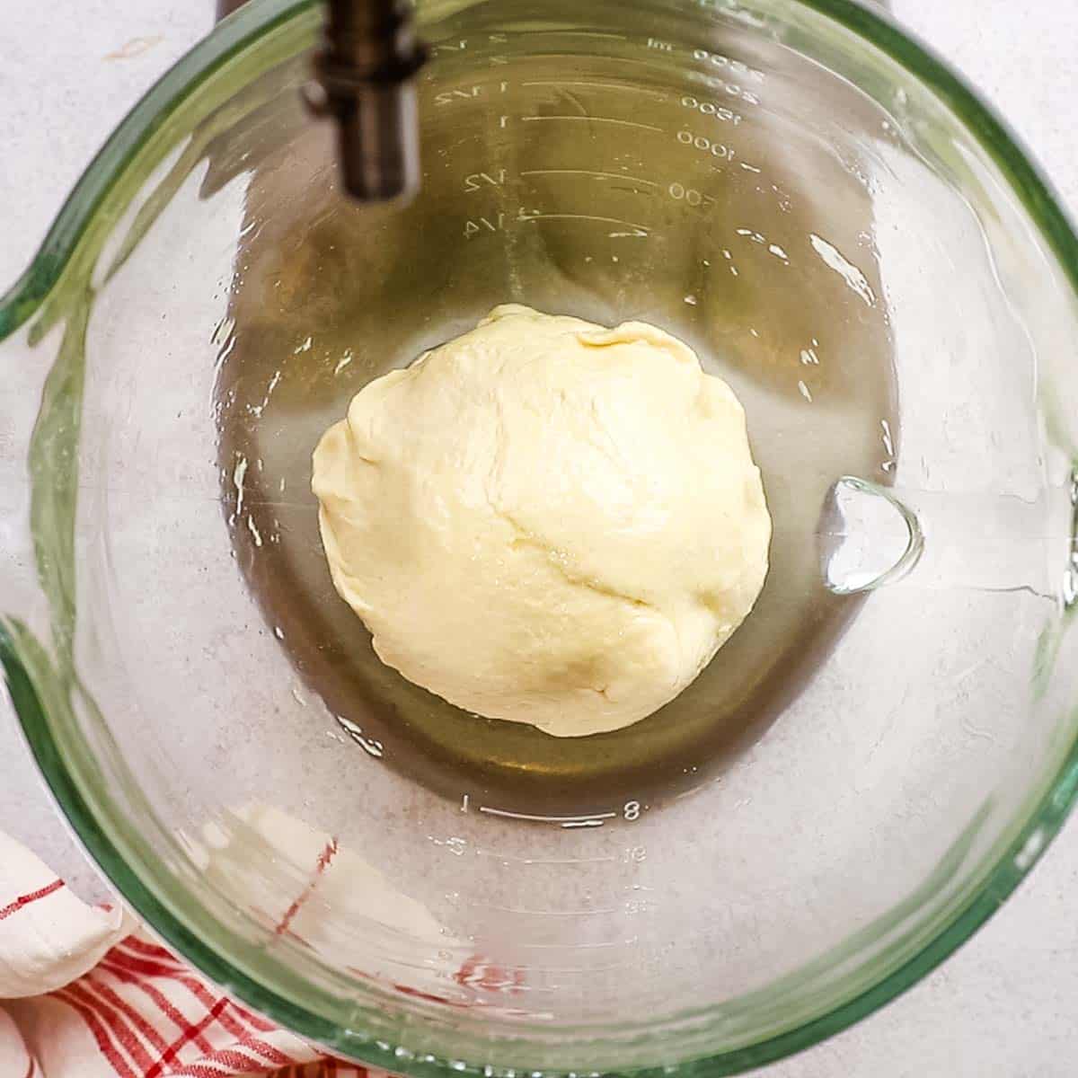 A ball of pizza dough in a mixer bowl before rising.