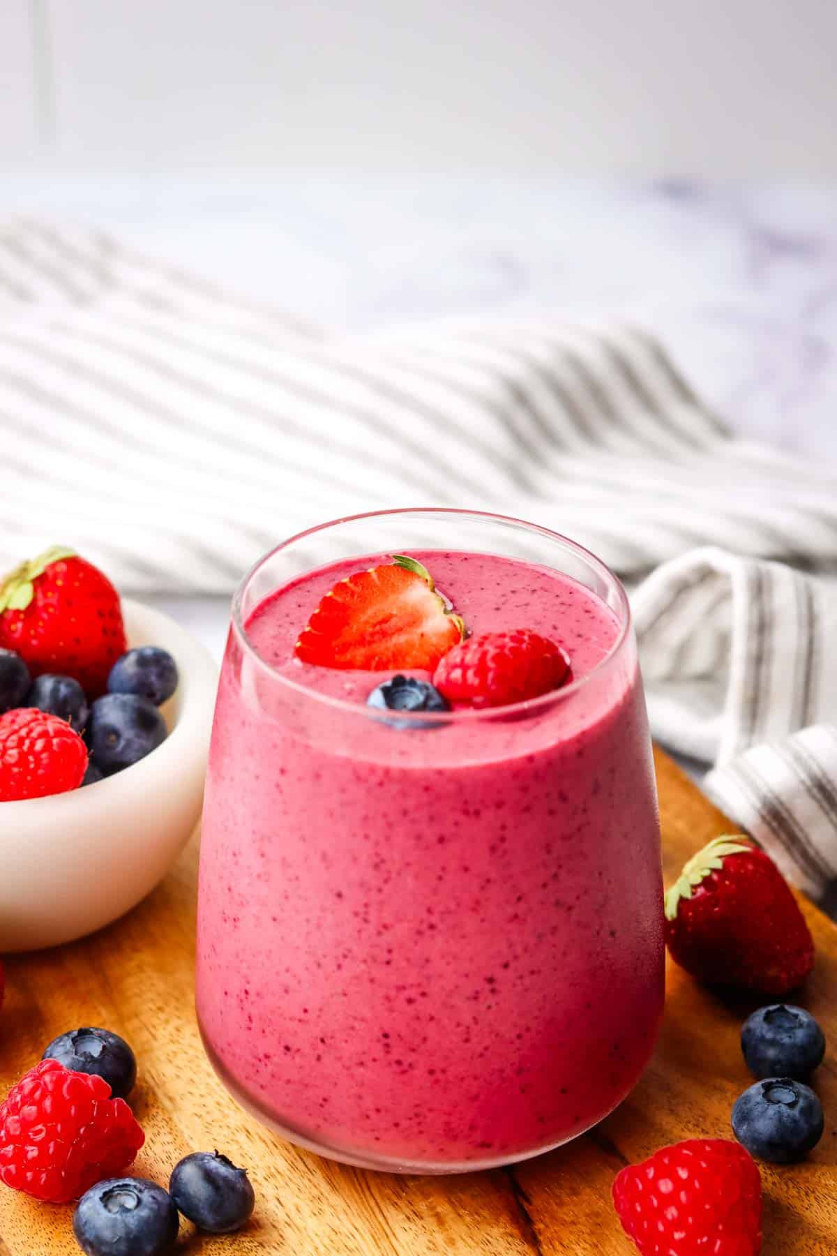 a glass of triple berry smoothie garnished with strawberries and blueberries