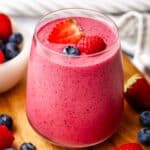 A berry smoothie in a glass garnished with berries.