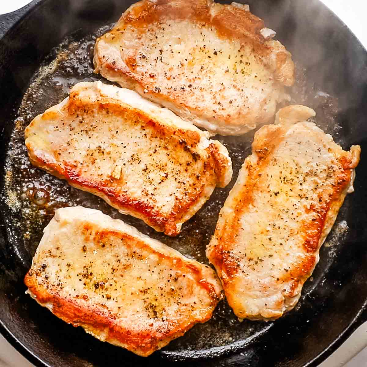browning pork chops in a cast iron skillet