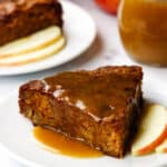 A slice of apple cake on a plate, drizzled with toffee sauce.