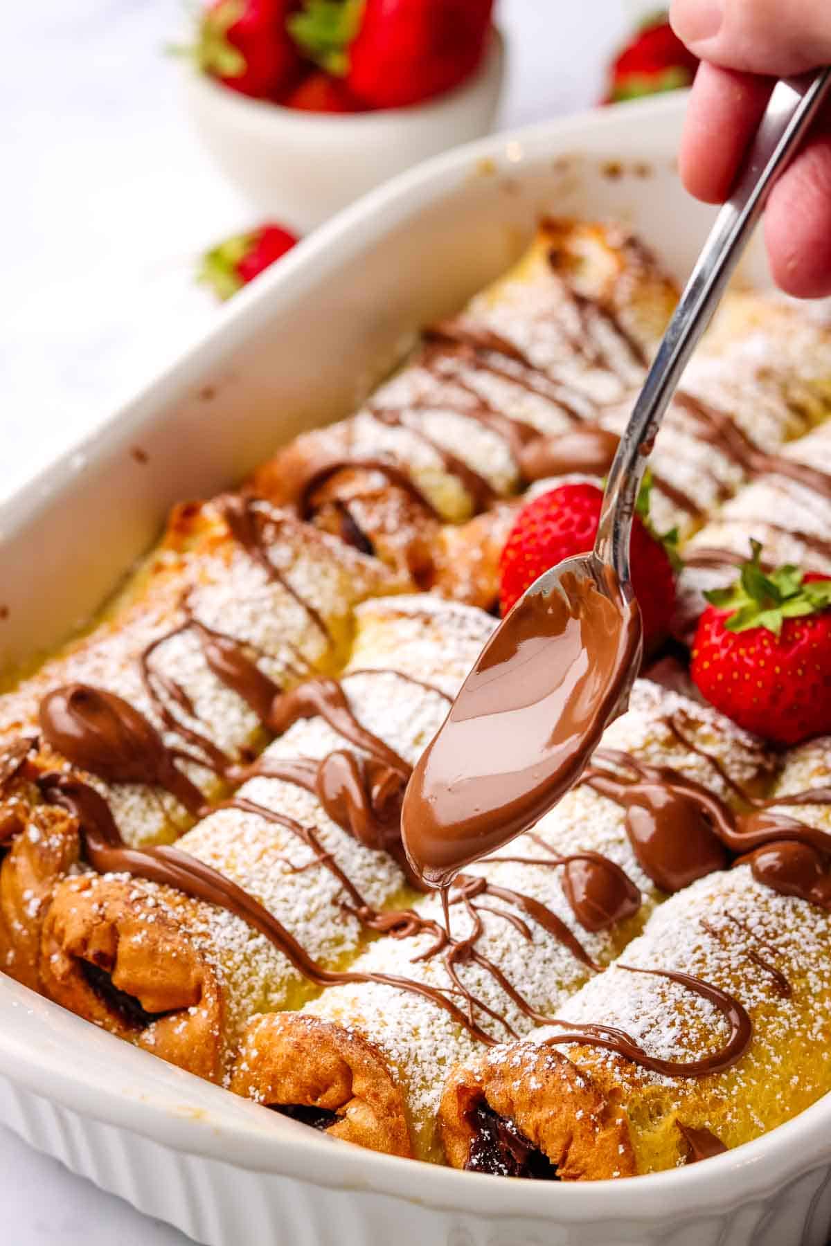 adding warm nutella over the french toast casserole