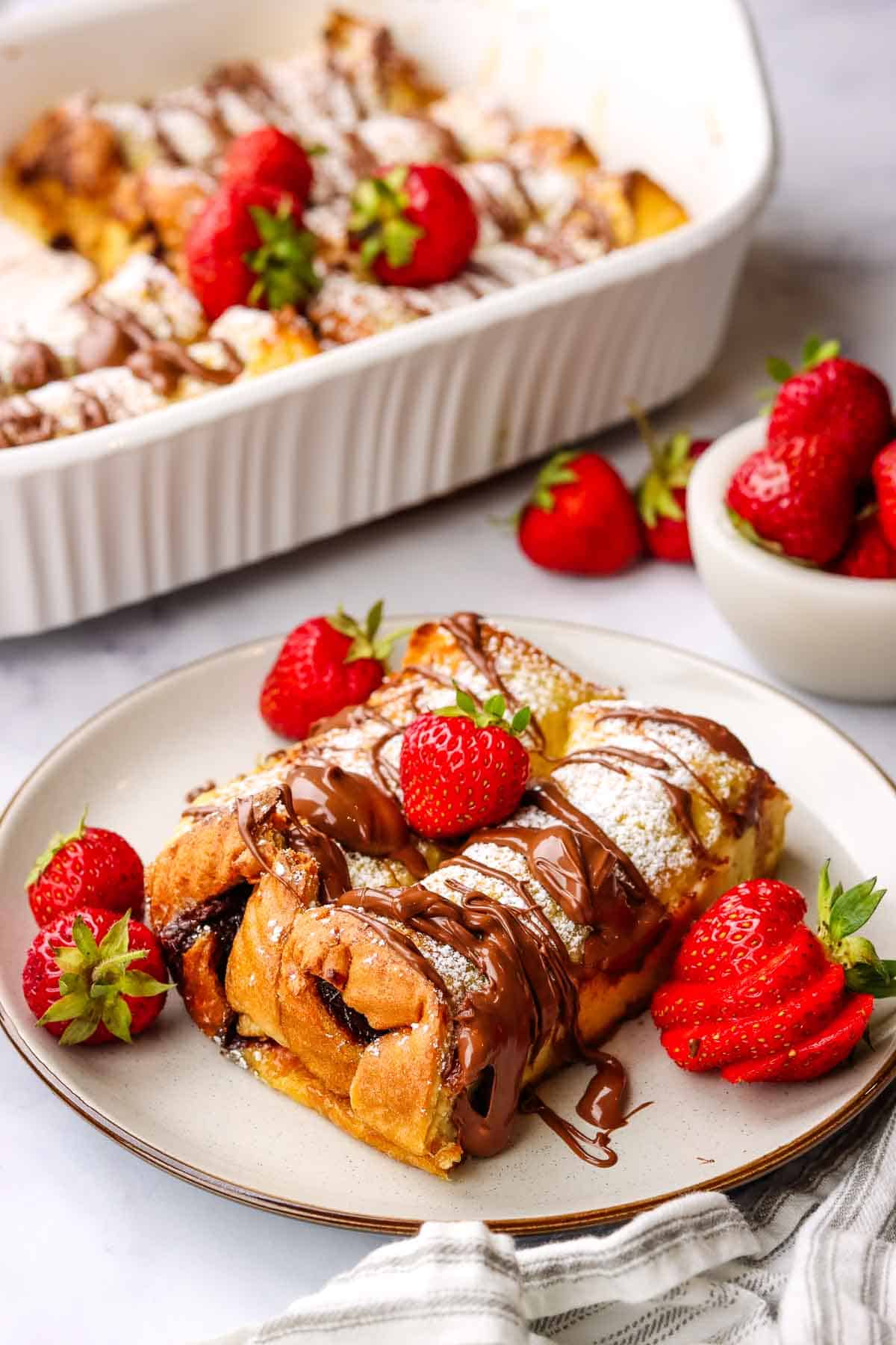 nutella french toast casserole served in a plate with the casserole dish in the background