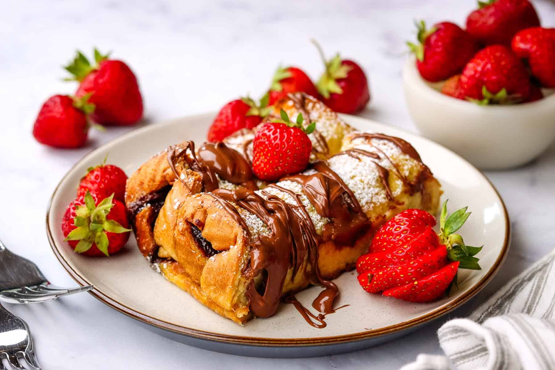 nutella french toast casserole served on a plate with fresh strawberries on the side