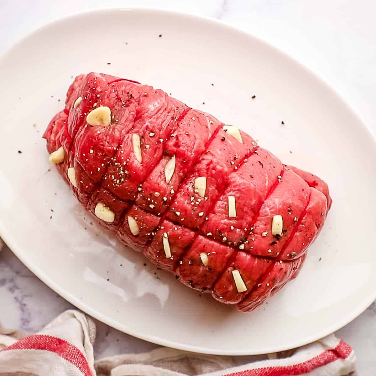 garlic stuffed in slits of a roast beef placed on a dish