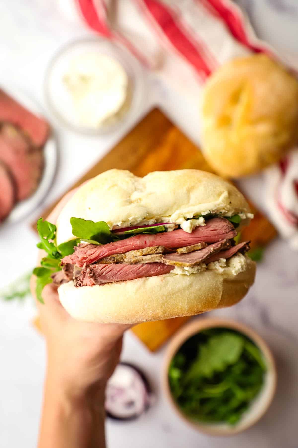 a hand holding a roast beef sandwich