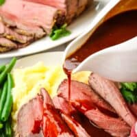 Gravy being poured over a plate of sliced roast beef.