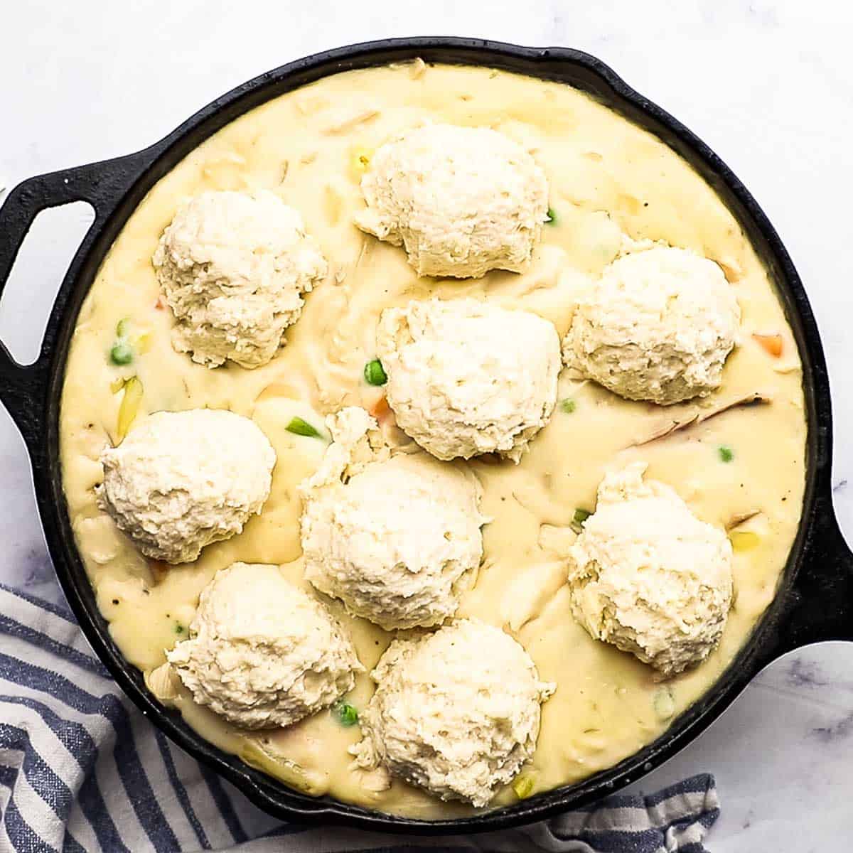 uncooked biscuit dough on top of the creamy chicken filling