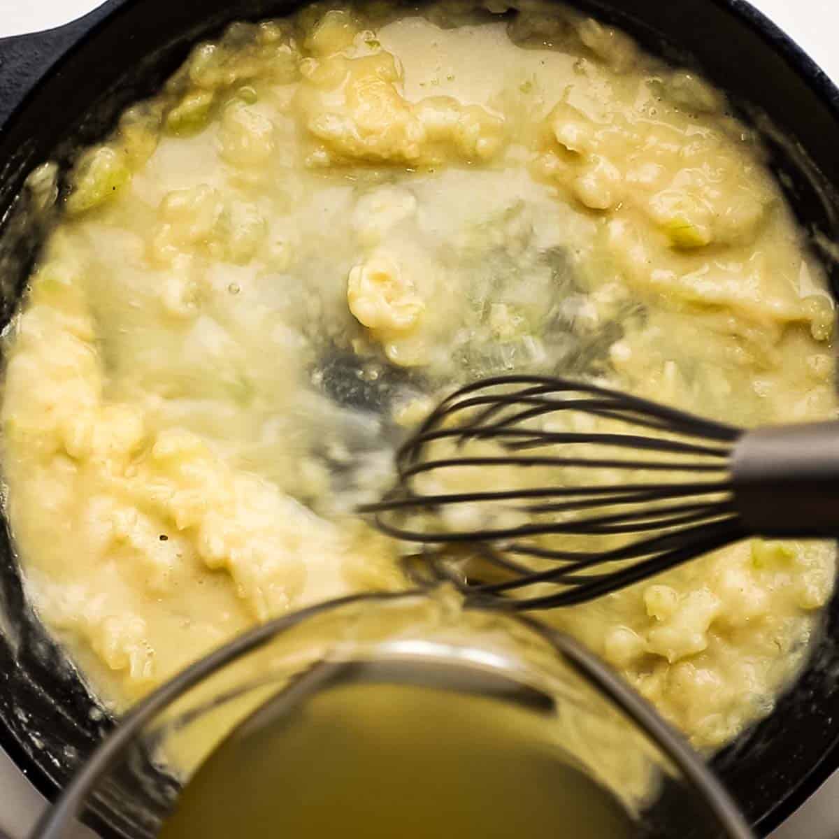 adding chicken broth to the skillet while whisking