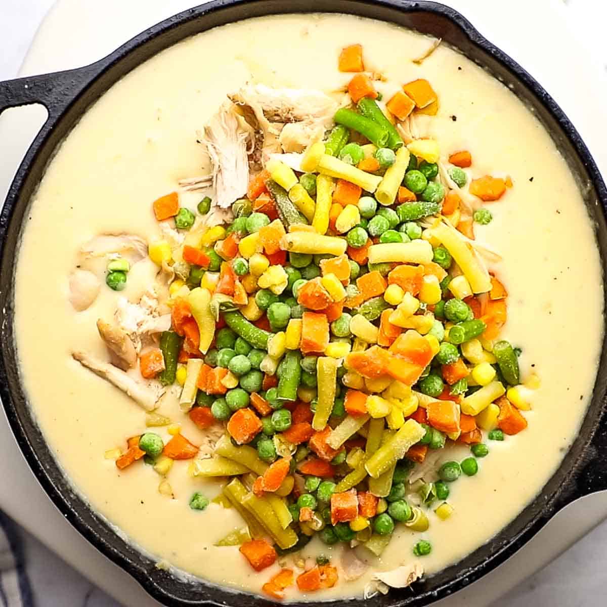 adding chicken and frozen veggies to the skillet