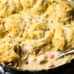 Closeup of chicken pot pie with biscuits with a spoon in it to show the filling.