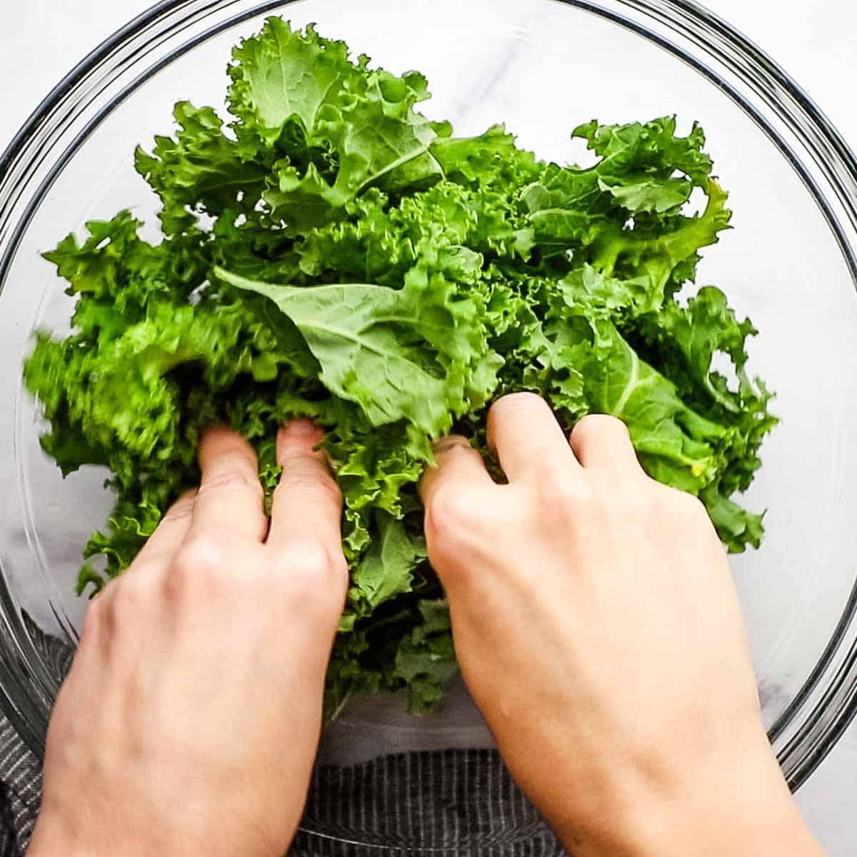 rubbing kale leaves with hands in a big bowl