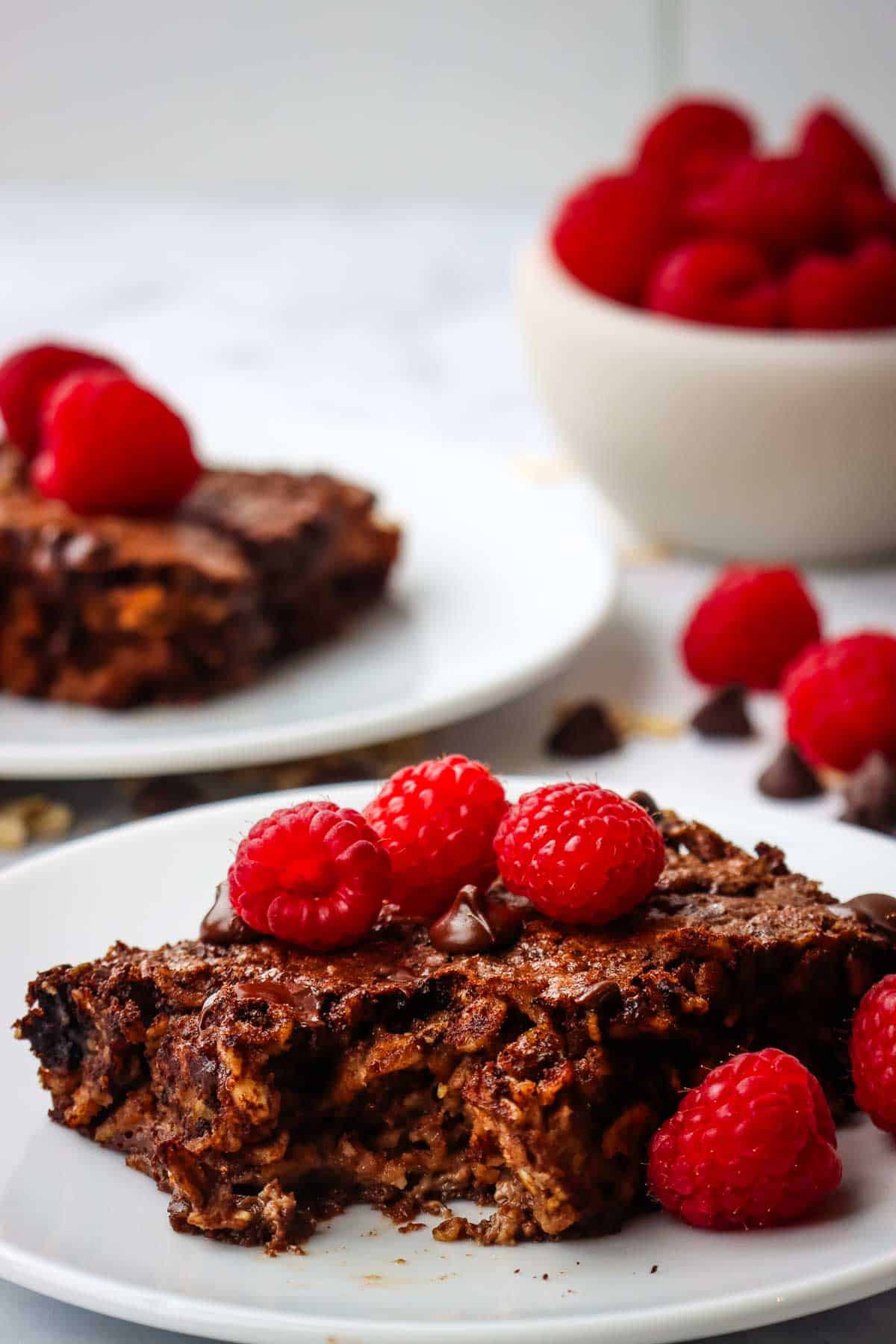 closeup of a slice of chocolate baked oats served with fresh raspberries