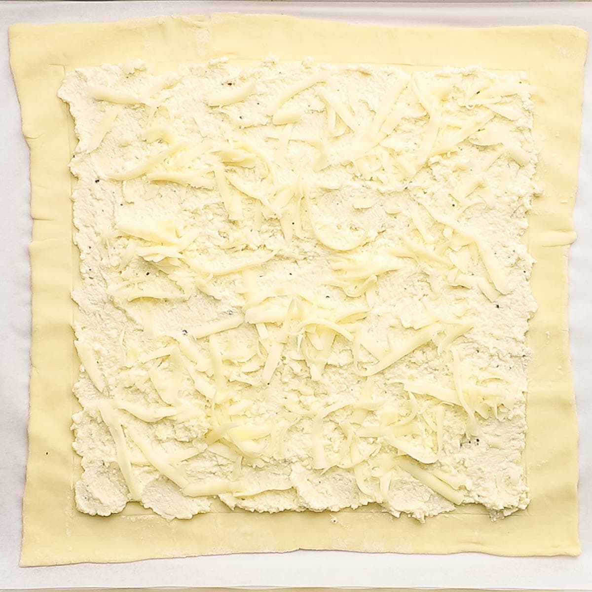 adding parmesan cheese on the puff pastry sheet