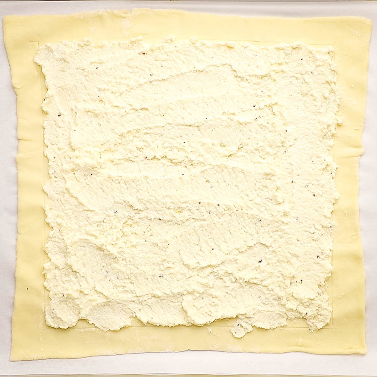 adding cheese filling in the middle of the puff pastry sheet