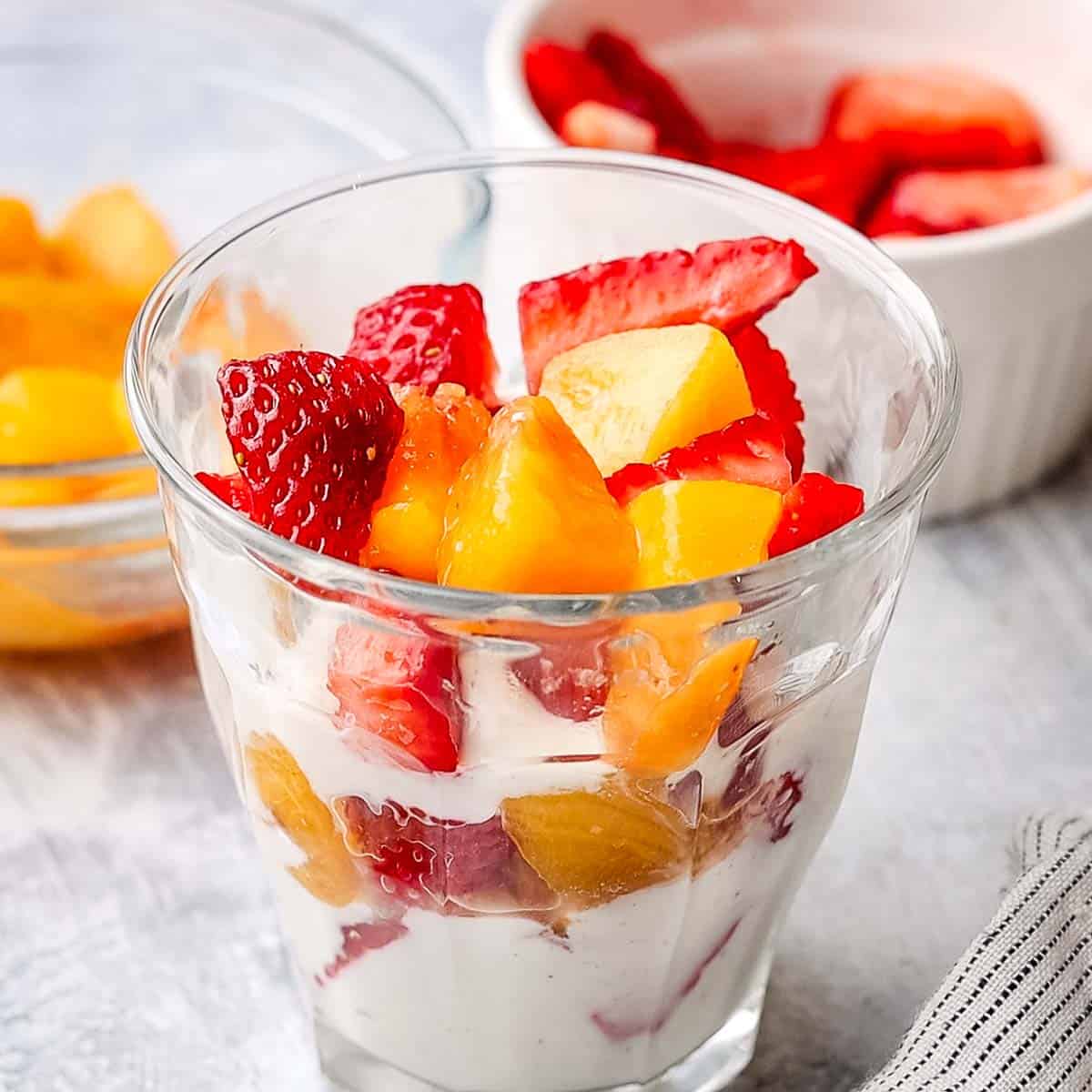 two layers of yogurt and fresh fruit in a small serving container