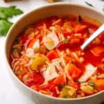 a bowl of minestrone soup with orzo, carrots, and onions in it
