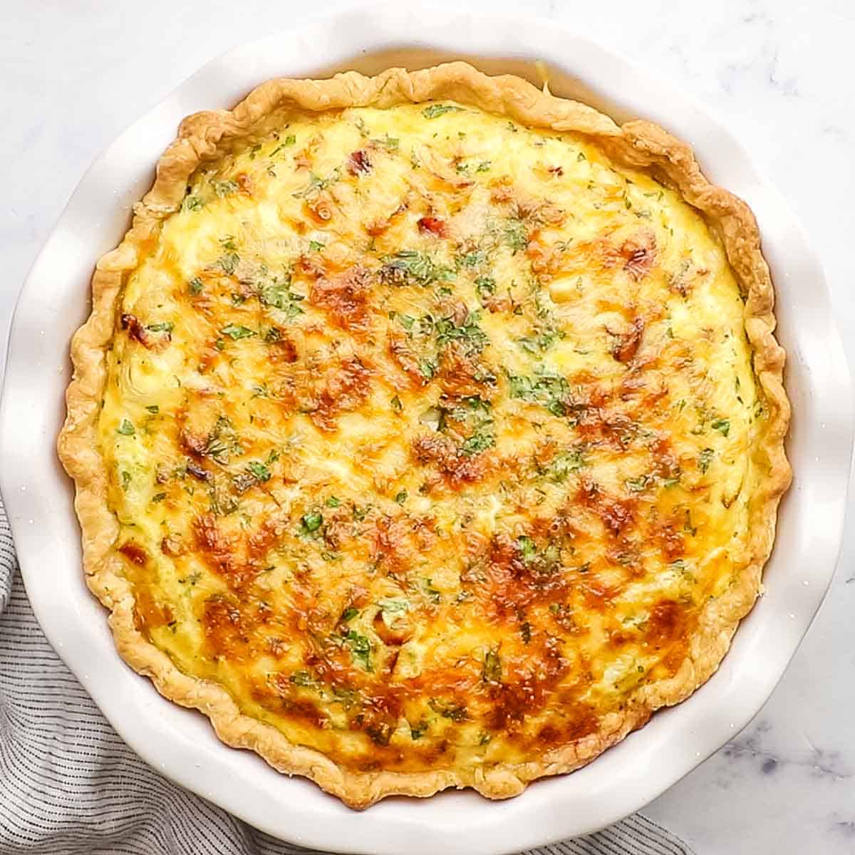 golden brown baked bacon and leek quiche in a pie dish