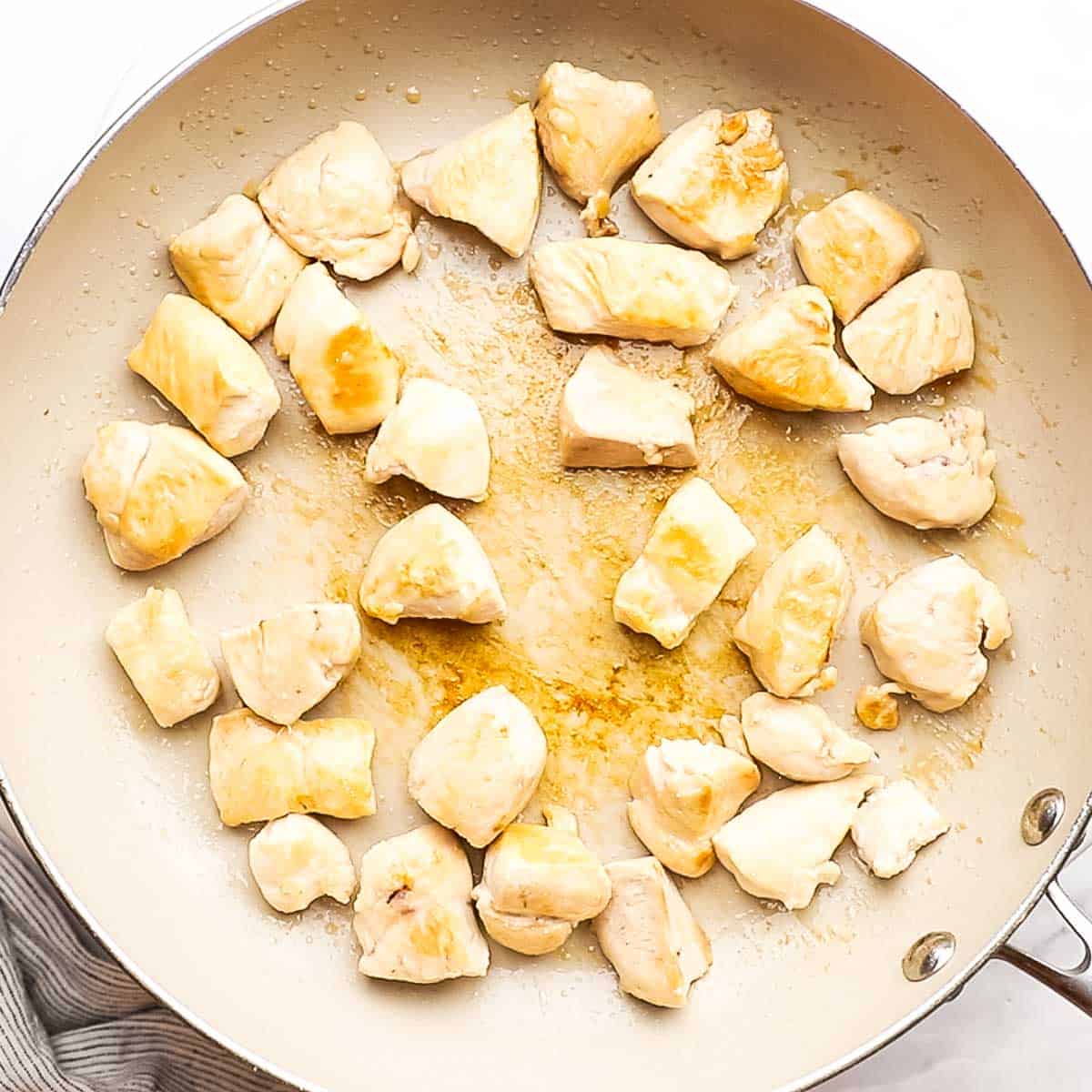 overhead view of chicken pieces being cooked in a skillet