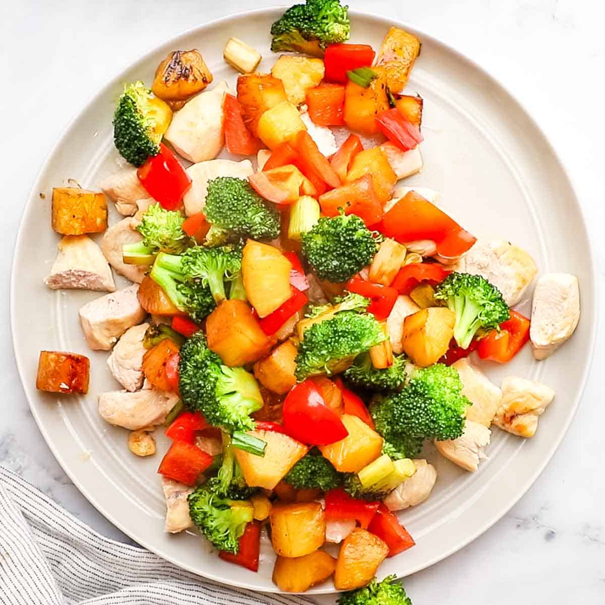 cooked chicken, veggies, and pineapple on a plate