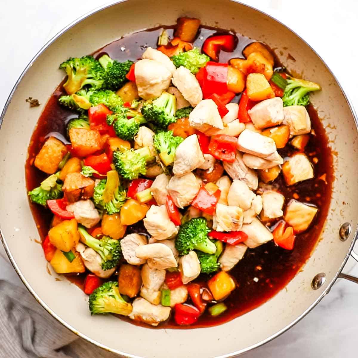 chicken, pineapple, and veggies added to the teriyaki glaze in a large skillet