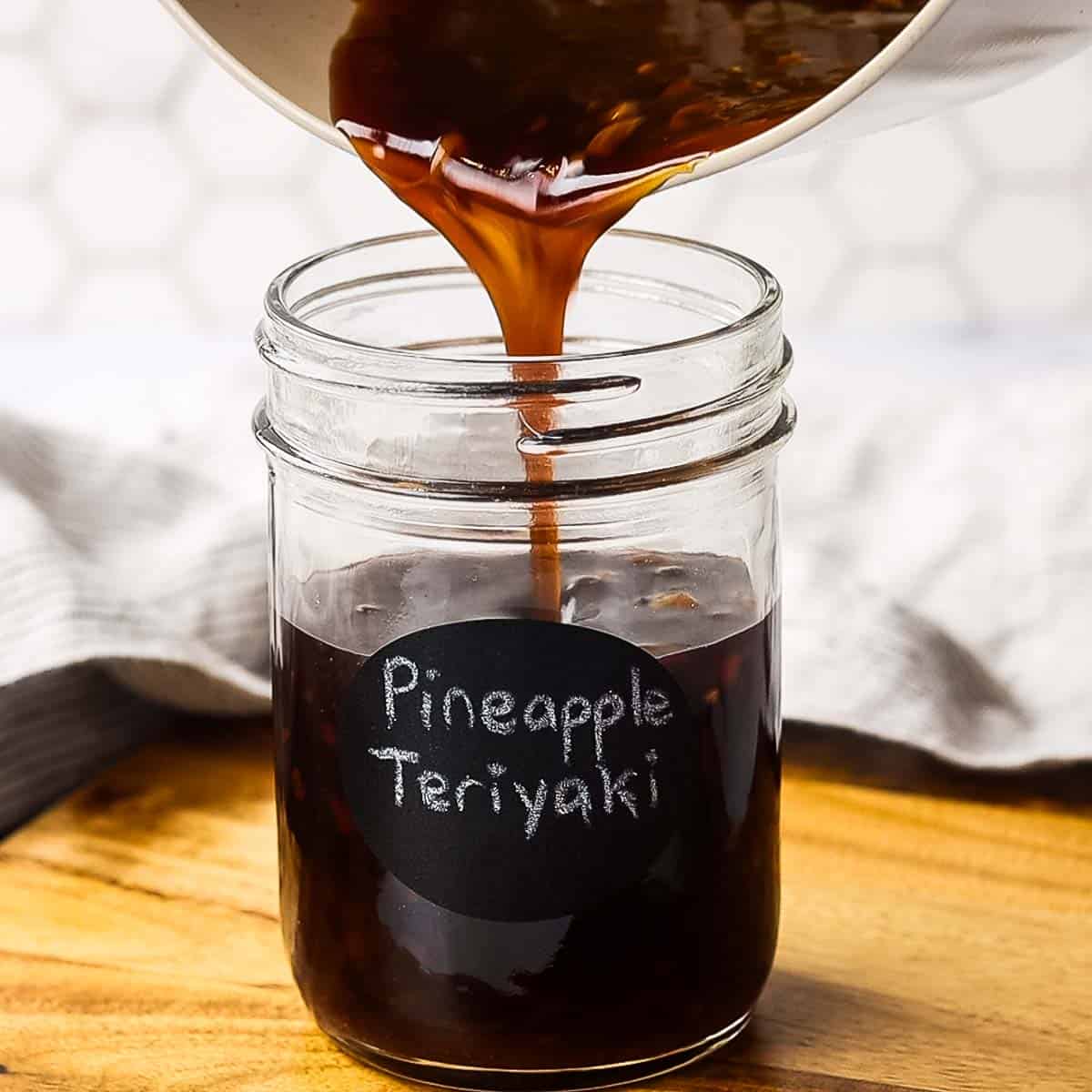 pouring pineapple teriyaki sauce in a jar labelled pineapple teriyaki