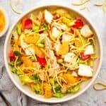 A bowl of Asian-inspired salad with chicken and mandarin oranges garnished with chow mein noodles.