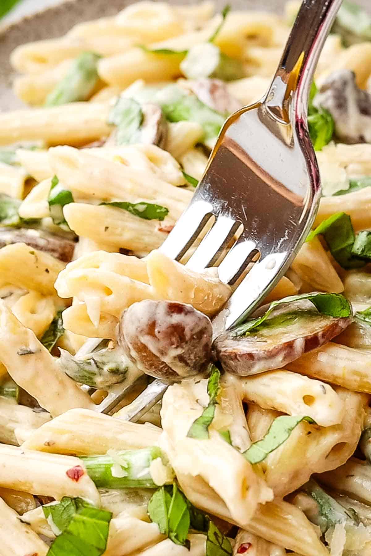 picking up a bite of asparagus mushroom pasta with a fork