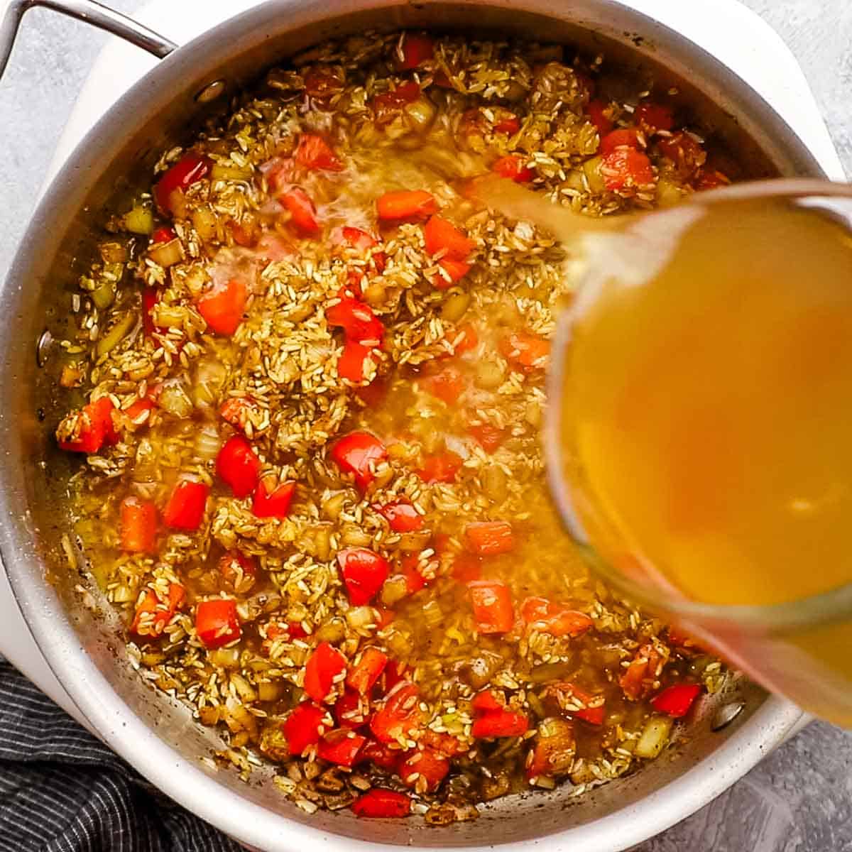 adding chicken broth to the pan