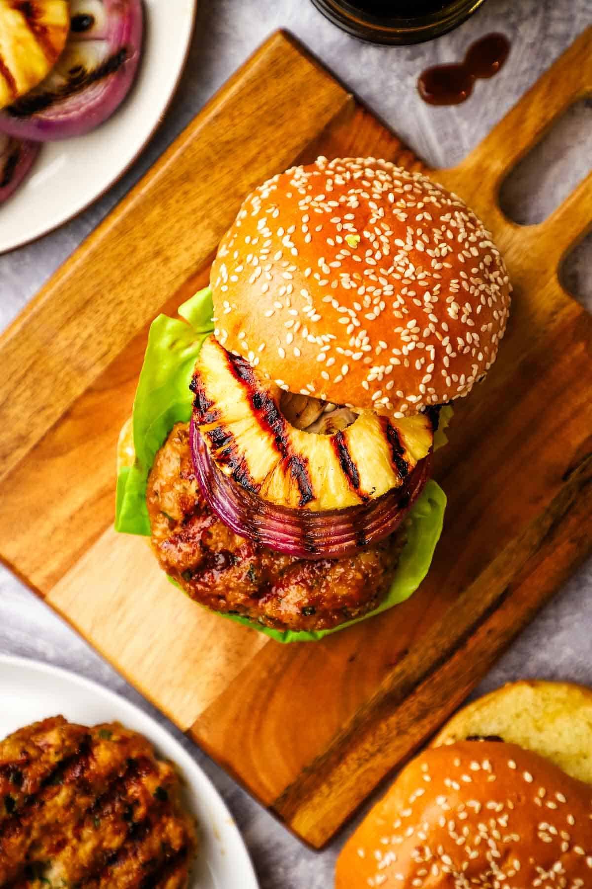 overhead view of a grilled chicken burger topped with a grilled pineapple slice.