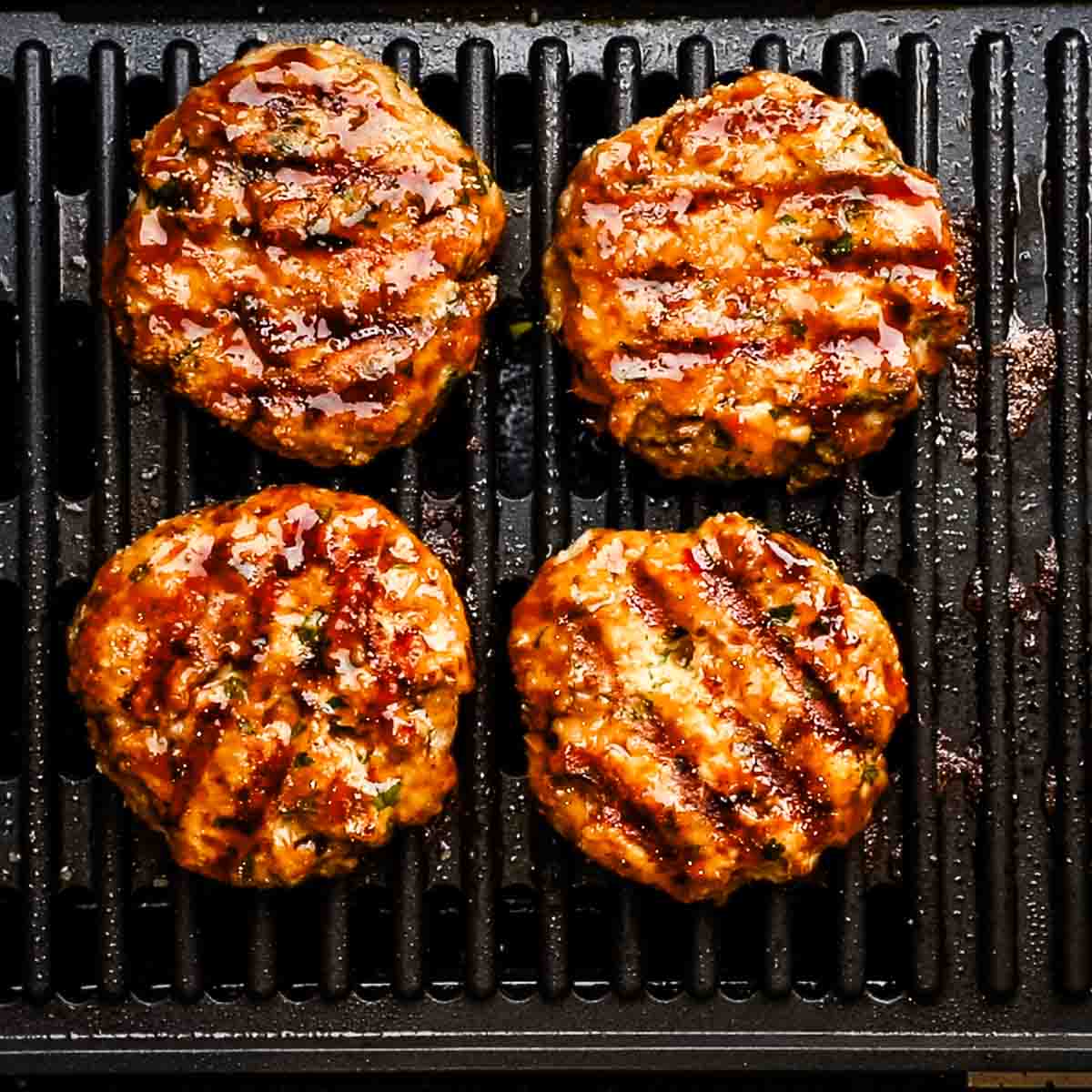 chicken patties brushed with teriyaki sauce cooking on a grill