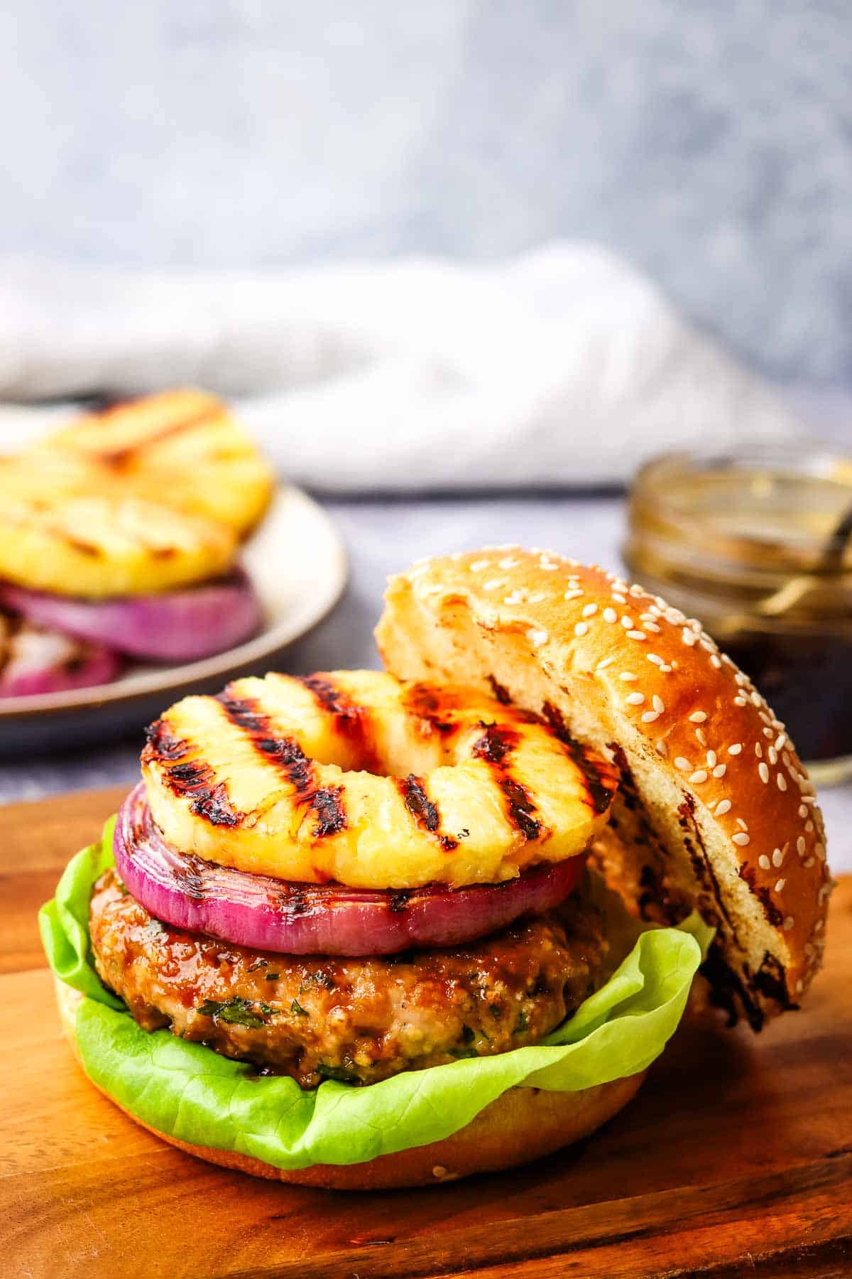 A grilled chicken burger topped with red onion and pineapple.
