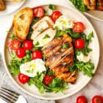 A plate of balsamic chicken salad with tomatoes and burrata cheese.