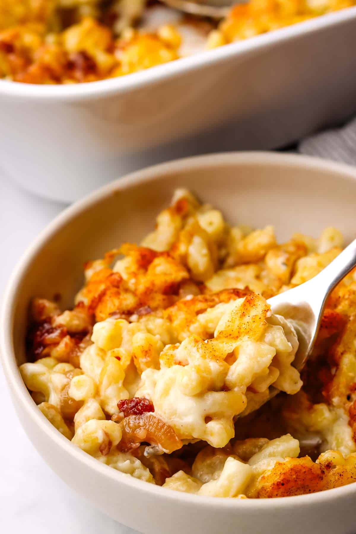 closeup of a bowl of mac and cheese with a spoon scooping up a bite.