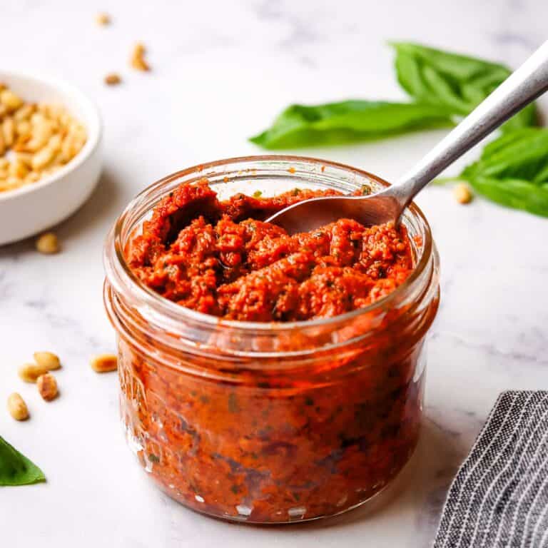 a jar of sun dried tomato pesto with a spoon in it.