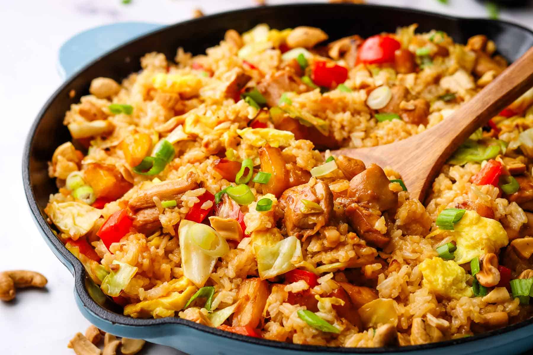 A pan of chicken fried rice with a serving spatula in it.