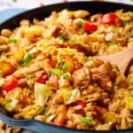 A skillet of chicken fried rice with a spatula in it.