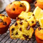 Orange chocolate chip muffins on a cooling rack with one split open.