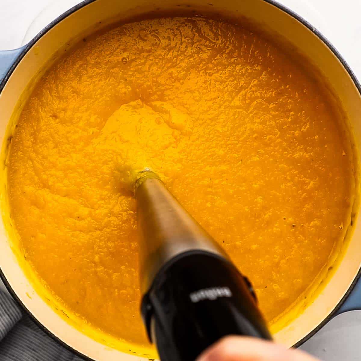 blending the soup with an immersion blender