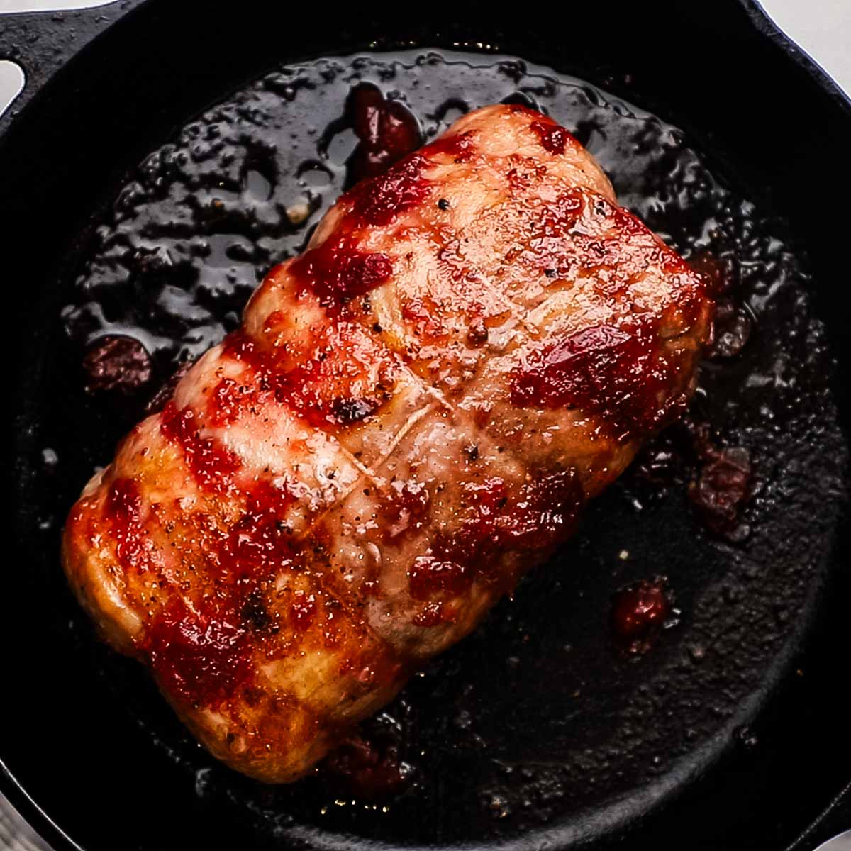 cooked cranberry glazed pork loin in a cast iron skillet