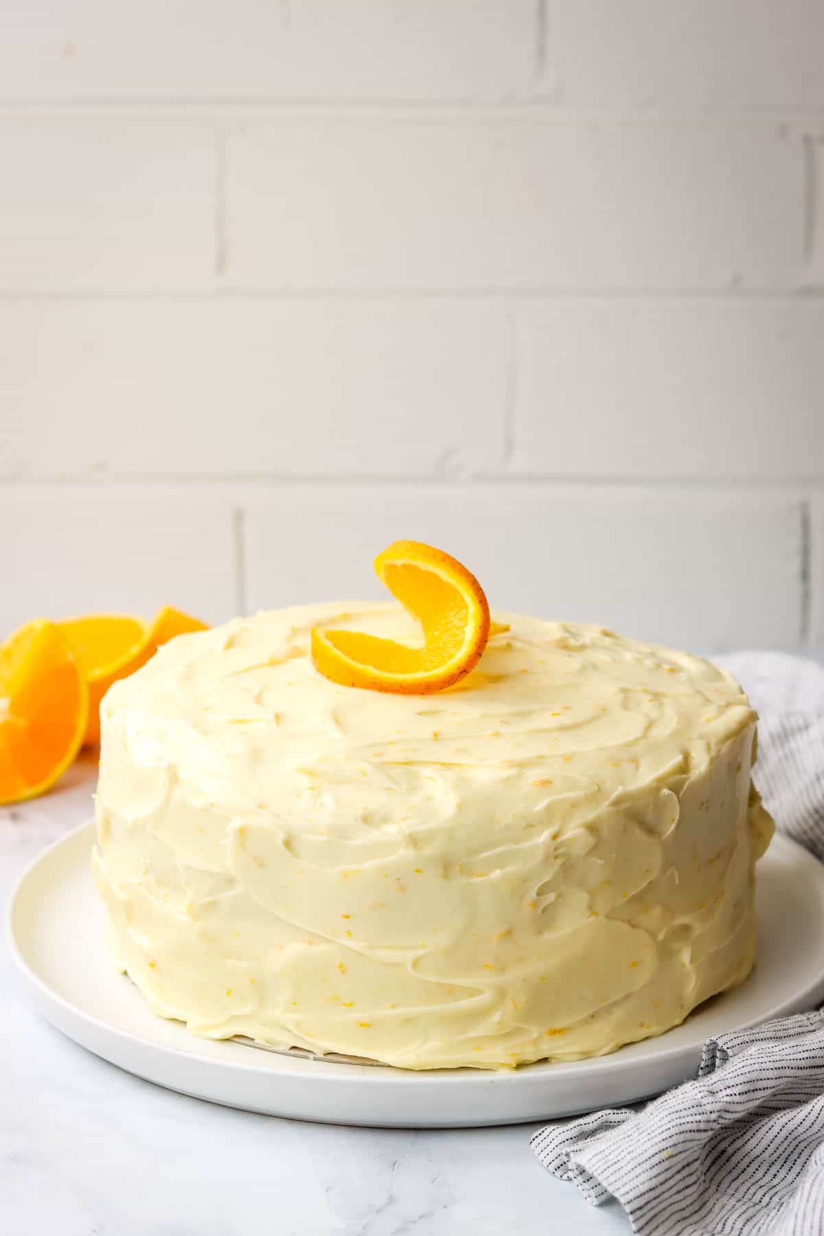 Orange cake with frosting decorated with an orange slice.